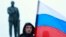 A man holds the Russian flag in front of a statue of Lenin in Simferopol, Crimea, on March 1, 2014.
