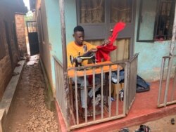 Timothy Kabogoza, a tailor who won first runner-up honors in the 2019-2020 Y+ Beauty Pageant, operates a sewing machine in front of his home in Bwyogerere, a Kampala slum, Nov. 25, 2019. (Halima Athumani/VOA)