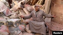 A survivor sits on the rubble of collapsed buildings at a site hit by what activists said was a barrel bomb dropped by forces loyal to Syria's President Bashar al-Assad in Aleppo's al-Sakhour district March 6, 2014. 