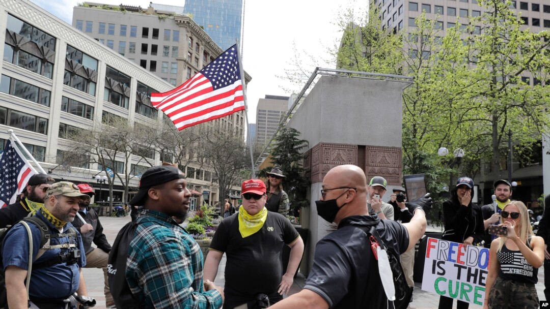 Members of a group wearing shirts with the logo of the far-right Proud Boys group argue with counter protesters during a small protest against Washington state's stay-at-home orders, Friday, May 1, 2020, in downtown Seattle.