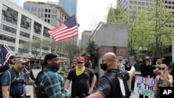 Members of a group wearing shirts with the logo of the far-right Proud Boys group argue with counter protesters during a small protest against Washington state's stay-at-home orders, Friday, May 1, 2020, in downtown Seattle.