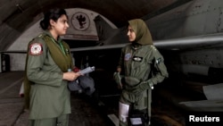 Ayesha Farooq, a fighter pilot, talks with avionics engineer Anam Hassan at Mushaf base in Sargodha, north Pakistan June 7, 2013.