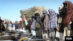 Mantan militan Taliban (tengah) memegang bendera nasional Afghanistan dalam sebuah upacara di kantor pemerintah di Ghazni, Afghanistan (16/1).