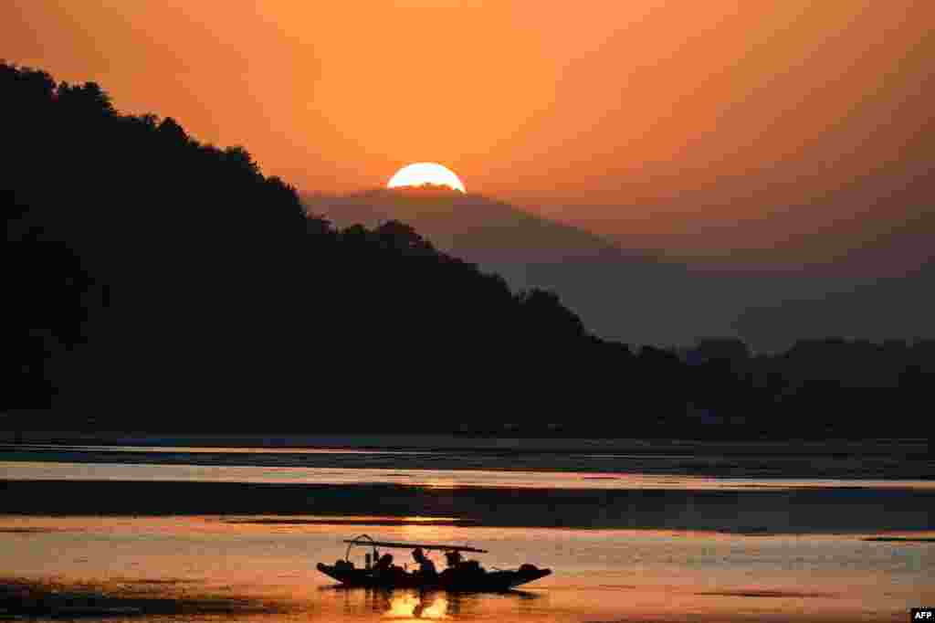Fishermen wait on a small boat after casting their net at Dal Lake during sunset in Srinagar, India.
