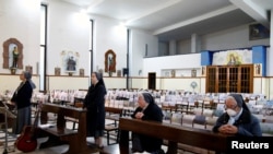 Nuns from the neighborhood of Librino attend a Holy Thursday Mass in a nearly empty church, with people replaced by children's drawings of congregation members in the pews, during the coronavirus lockdown in Catania, Italy, April 9, 2020.