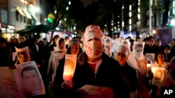 Para demonstran membawa lilin dan foot beberapa dari 43 mahasiswa yang hilang, di Mexico City, Jumat, 14 November 2014. (AP Photo/Eduardo Verdugo)