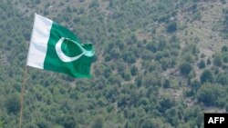 FILE - A Pakistani flag flies at Manatu mountain in the central part of Kurram Agency, Pakistan's tribal belt bordering Afghanistan, July 10, 2011. 