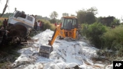 An excavator clears bags of white cement scattered on a road after a truck accident near Auraiya, a village in Uttar Pradesh state, India, May 16, 2020. 