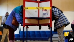 Caution tape closes off a voting stall to help distance voters to help prevent the spread of the coronavirus on Election Day, Nov. 3, 2020, in Portland, Maine.