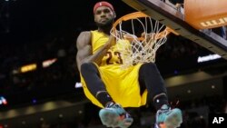 Cleveland Cavaliers forward LeBron James (23) hangs onto the basket after a dunk during the second half of an NBA basketball game against the Miami Heat in Miami, Dec. 25, 2014. James was called for a technical foul on the play.