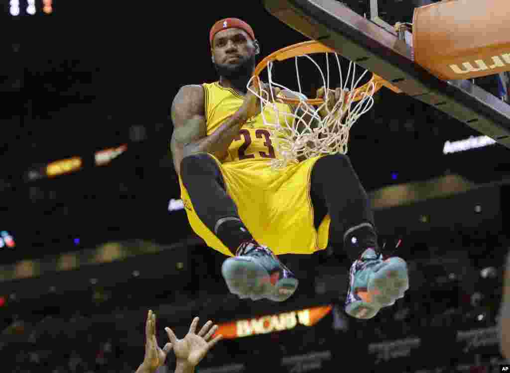 Cầu thủ LeBron James của đội Cleveland Cavaliers đu lên rổ sau một pha bỏ bóng trong một trận đấu bóng rổ NBA với đội Miami Heat ở thành phố Miami, bang Florida, Mỹ, ngày 25 tháng 12, 2014. Pha bỏ bóng này bị thổi còi vì phạm lỗi kỹ thuật.