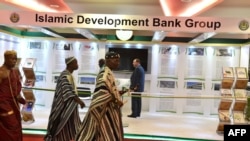 FILE - Traditional chiefs walk past an Islamic Development Bank Group stand during a meeting of the Ministers of Foreign Affairs of the Organization of Islamic Cooperation (OIC) in Abidjan, July 10, 2017.