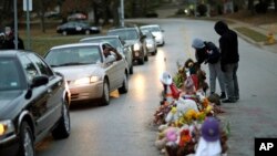 Protesters gather near a memorial in the middle of the street, Nov. 24, 2014, more than three months after a black 18-year-old man was shot and killed there by a white policeman in Ferguson, Mo. 