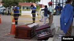 Orang-orang menunggu di sebelah peti mati di luar Rumah Sakit Umum Guasmo Sur setelah Ekuador melaporkan kasus corona di Guayaquil, Ekuador 1 April 2020. (Foto: Reuters/Vicente Gaibor del Pino)