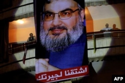 Poster pemimpin Hizbullah Lebanon Hassan Nasrallah dengan slogan berbahasa Arab "Kami merindukanmu" tergantung di sebuah gedung pada 18 Juli 2012. (Foto: AFP)