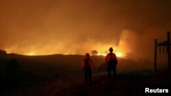 Dua petugas pemadam kebakaran memantau kebakaran Kincade, di dekat Geyserville, California, AS, 24 Oktober 2019.