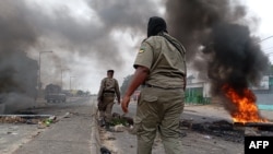 TOPSHOT - Mozambican security forces are seen next to a burning barricade in Maputo on December 24, 2024.