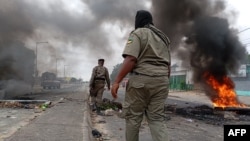 Mozambican security forces walk near a burning barricade in Maputo on Dec. 24, 2024. South Africa has rerouted border traffic in response to the violence in neighboring Mozambique.