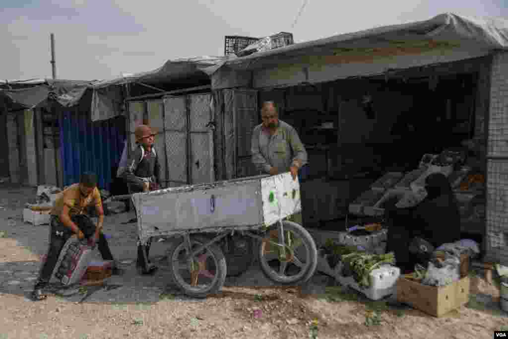 A man and two young boys bring food and drinks to be sold in the market area of al-Hol Camp, the largest prison camp in Northeast Syria, on Oct. 12, 2024. (Diego Baravelli/VOA) 