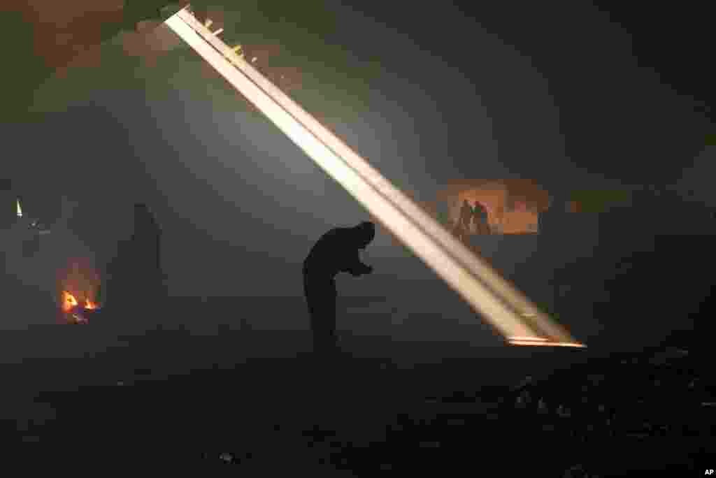 A group of migrants, left, gather around a fire to warm themselves in an abandoned warehouse in Belgrade, Serbia, Jan. 30, 2017. Hundreds of migrants have been sleeping in freezing conditions in central Belgrade looking for ways to cross the heavily guarded EU borders.