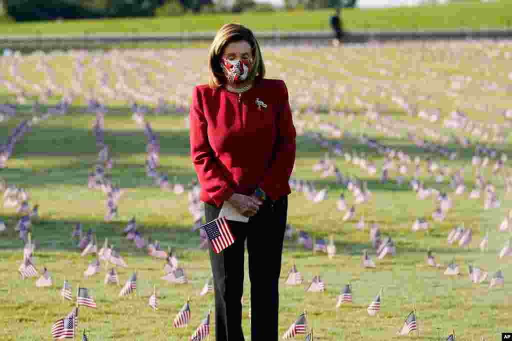 House Speaker Nancy Pelosi looks at small flags placed on the grounds of the National Mall by activists from the COVID Memorial Project to mark the deaths of 200,000 lives lost in the U.S. to COVID-19, in Washington.