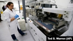 Caitlin Cramer, a PhD student in materials science engineering, demonstrates a machine that can produce electrical circuits and solar cells at the newly opened Washington Clean Energy Testbeds laboratory housed in the University of Washington's Clean Ener