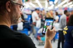 Customer uses his phone as a shopping tool during Black Friday at Walmart in Bentonville, Arkansas, Nov. 24, 2016.