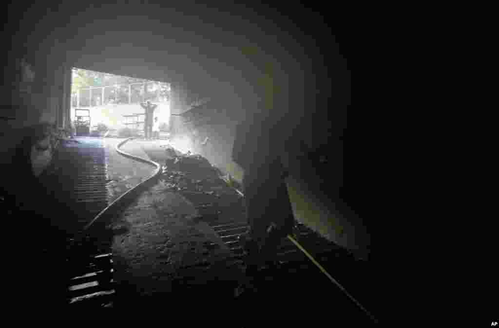 A firefighter walks into the basement of the hospital to douse the fire. (AP/Anupam Nath)