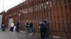 (FILE) Federal officers remove handcuffs from men before releasing them through a gate in a border wall to Tijuana, Mexico, Wednesday, March 15, 2023, in San Diego.