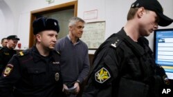 Founder of the Baring Vostok investment fund Michael Calvey, center, is escorted to the courtroom in Moscow, Feb. 15, 2019. A veteran U.S. investment fund manager has been detained in Moscow and faces fraud charges.