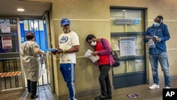 People who were just tested for COVID-19 wait in line to make payment for the test at a private laboratory in Johannesburg, South Africa, Dec. 19, 2020.