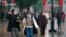 Masked pedestrians walk down a shopping street in downtown Wuhan, China, Wednesday,  Jan. 22, 2020. The number of cases of a new coronavirus from Wuhan has risen over 400 in China and the death toll to 9, Chinese health authorities said.