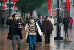 Masked pedestrians walk down a shopping street in downtown Wuhan, China, Wednesday, Jan. 22, 2020. The number of cases of a new coronavirus from Wuhan has risen over 400 in China and the death toll to 9, Chinese health authorities said Wednesday. …