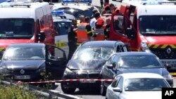 French security forces and emergency vehicles surround a car, center, on a highway between Boulogne-sur-Mer and Calais in northern France that authorities say was used in an attack on soldiers near Paris, Aug. 9, 2017. 