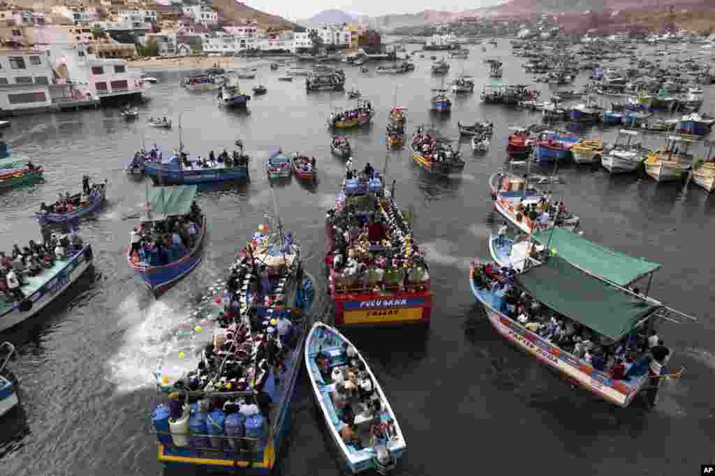 Pescadores van en procesión detrás de la representación de San Pedro, transportada en un bote, en el centro, como parte de la procesión por el océano Pacífico en honor del santo patrón católico de los pescadores en el día de su festividad en Pucusana, Perú, el jueves 29 de junio de 2023.