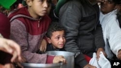 FILE - Palestinians line up for free food distribution during the ongoing Israeli air and ground offensive in Khan Younis, Gaza Strip, February 2, 2024