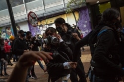 Demonstrators escape from tear gas during a national protest against President Duque’s proposed tax reform in Bogotá, Colombia, April 28, 2021. (Pu Ying Huang/VOA)