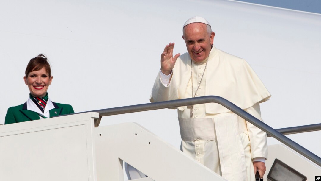 Paus Fransiskus melambaikan tangan ke arah wartawan di bandara internasional Roma, Minggu (5/7) sebelum memasuki pesawat menuju Quito, Ekuador. (AP/Riccardo De Luca)