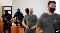 Marian Kocner is surrounded by armed police officers in the courtroom after a trial against him in Pezinok, Slovakia, Sept. 3, 2020.
