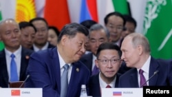 Russian President Vladimir Putin, right, and Chinese President Xi Jinping speak during a plenary session in the outreach/BRICS Plus format at the BRICS summit in Kazan, Russia, Oct. 24, 2024.