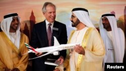 Глава компании Boeing Джеймс Макнирни (второй слева) показывает премьеру ОАЭ шейху Мохаммеду бин Рашиду аль Мактуму (второй справа) модель новой модификации дальнемагистрального лайнера «Boeing 777X». Дубай 17 ноября 2013 г.