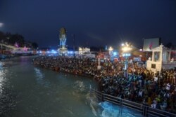 Devotees gather for an evening prayer on the banks of the Ganges river during Kumbh Mela, or the Pitcher Festival in Haridwar, India, April 12, 2021.