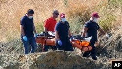 A crew carries what are believed to be remains of a 6-year-old girl, near Xiliatos, Cyprus, June 12, 2019. Cyprus authorities believe the girl was the victim of a confessed serial killer, a Cyprus army captain.