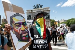 Un hombre usa una bandera de Guyana como protegerse la cara mientras escucha a los oradores durante un mitin de Black Lives Matter.