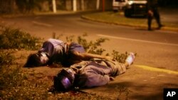 FILE - Bodies of two victims of Mexico's ongoing drug war are seen lying by the side of a road as police secure the area in the city of Veracruz, Mexico.