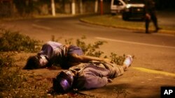 FILE - Bodies of two victims of Mexico's ongoing drug war are seen lying by the side of a road as police secure the area in the city of Veracruz, Mexico.