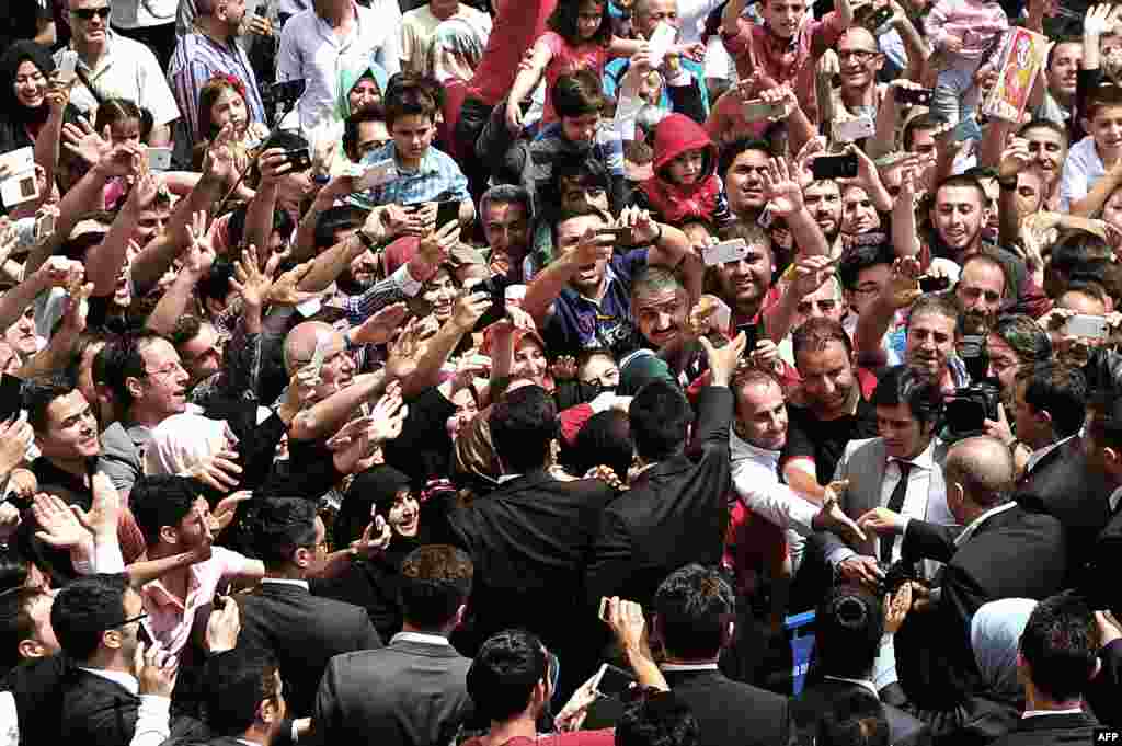 Presiden Turki Recep Tayyip Erdogan (bawah kanan) bersalaman dengan pendukungnya di luar TPS setelah ia memberikan suaranya untuk pemilihan legislatif Turki di Istambul.