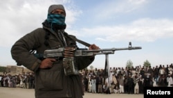FILE - A member of the Taliban and other people stand at the site during the execution of three men in Ghazni Province, Afghanistan, April 18, 2015. On Feb. 22, 2024, Taliban authorities publicly executed two men convicted of murder in separate cases.