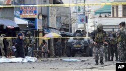 FILE - Police investigators and soldiers attend the scene after two bombs exploded outside a Roman Catholic cathedral in Jolo, the capital of Sulu province in southern Philippines, Jan. 27, 2019.