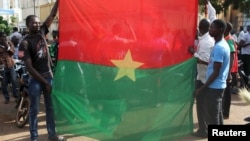 Warga melakukan unjuk rasa anti-kudeta dengan membentangkan bendera nasional Burkina Faso di ibukota Ouagadougou, Selasa (22/9).